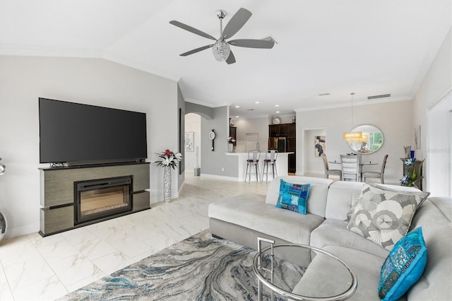 living room with ceiling fan with notable chandelier, ornamental molding, and vaulted ceiling