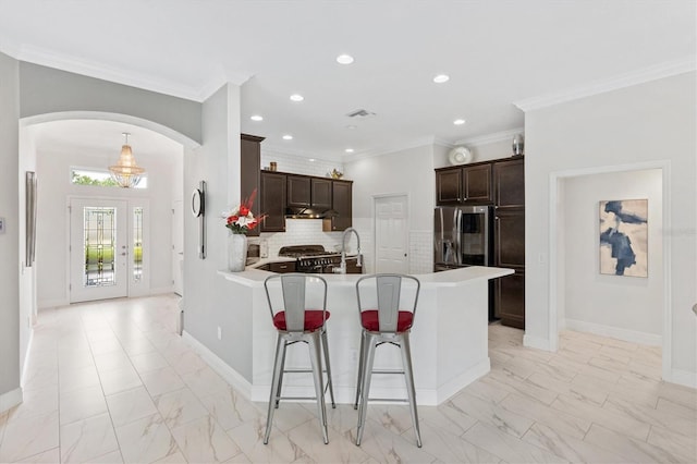 kitchen featuring stainless steel refrigerator with ice dispenser, kitchen peninsula, crown molding, a kitchen bar, and decorative backsplash