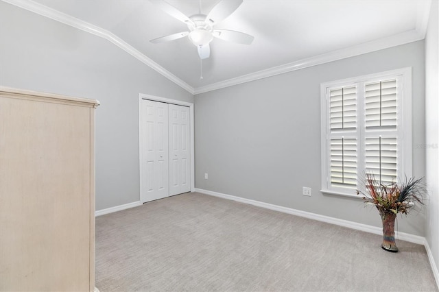 unfurnished bedroom featuring ceiling fan, lofted ceiling, light carpet, a closet, and ornamental molding