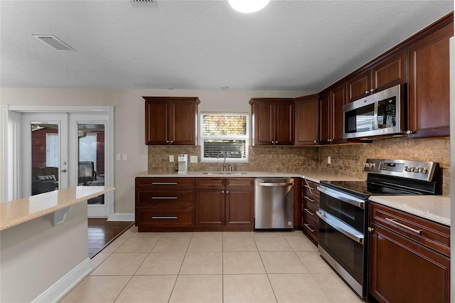 kitchen featuring light tile patterned flooring, sink, appliances with stainless steel finishes, and french doors