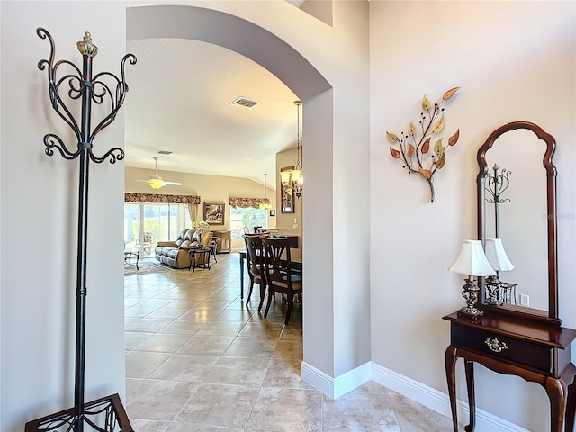 hall with light tile patterned floors and vaulted ceiling