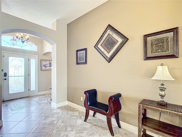 tiled entryway with a notable chandelier and a textured ceiling