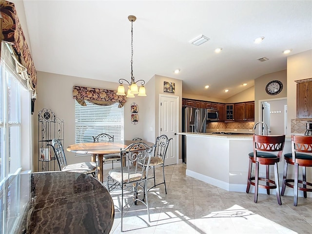 dining space with light tile patterned floors, a notable chandelier, and vaulted ceiling