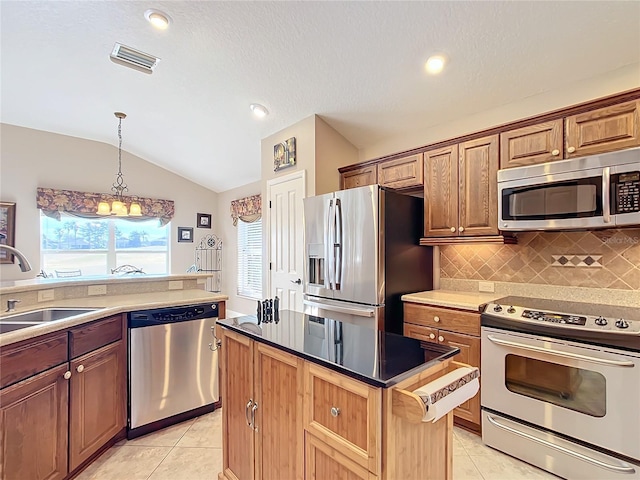 kitchen featuring sink, a center island, light tile patterned floors, appliances with stainless steel finishes, and pendant lighting