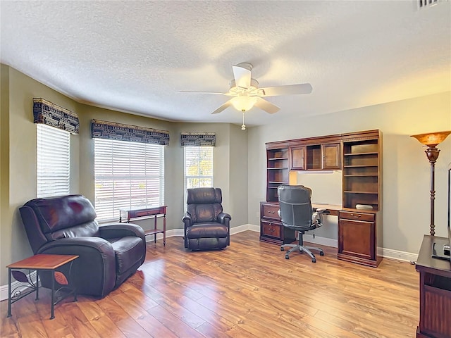 office space featuring ceiling fan, light hardwood / wood-style flooring, and a textured ceiling