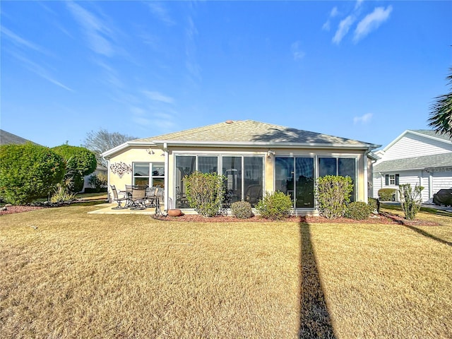 back of house with a sunroom, a patio area, and a lawn