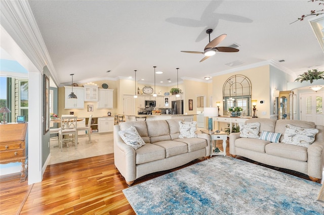 living room featuring ceiling fan, light wood-type flooring, crown molding, and vaulted ceiling