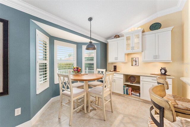 tiled dining space with ornamental molding and vaulted ceiling