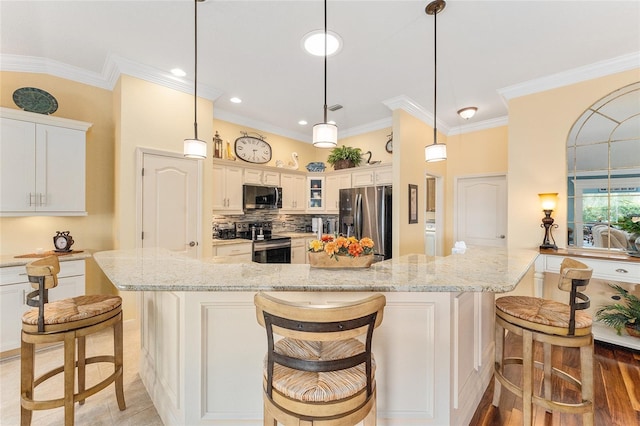 kitchen with light stone counters, pendant lighting, a kitchen bar, white cabinets, and appliances with stainless steel finishes