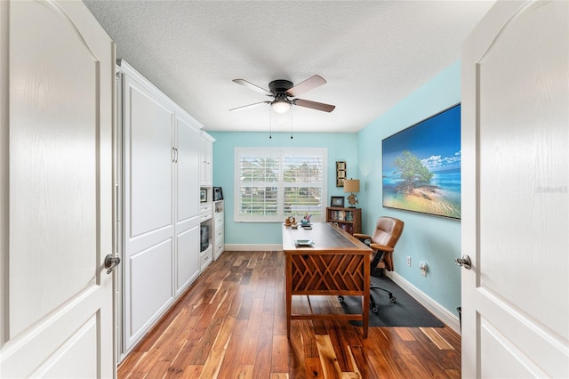 home office featuring dark hardwood / wood-style floors, ceiling fan, and a textured ceiling