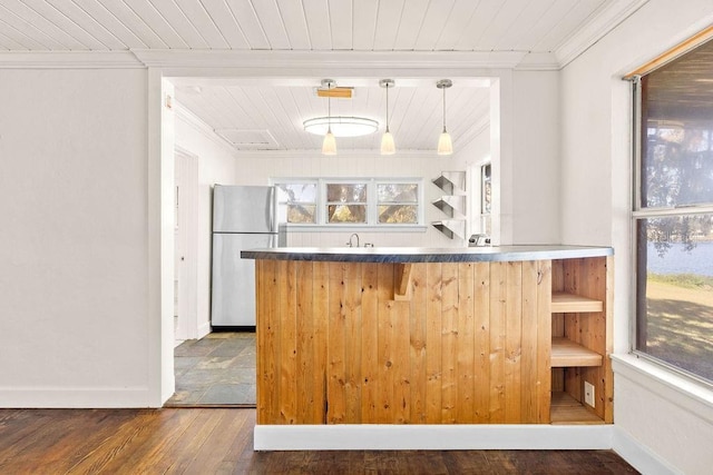 kitchen with pendant lighting, dark hardwood / wood-style flooring, crown molding, and stainless steel refrigerator