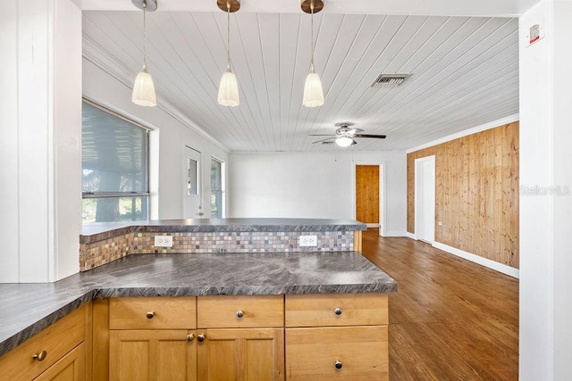 kitchen featuring decorative light fixtures, ceiling fan, wooden walls, ornamental molding, and dark hardwood / wood-style flooring