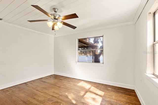 empty room featuring ceiling fan, plenty of natural light, crown molding, and hardwood / wood-style floors