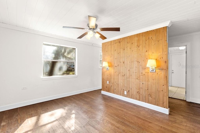 spare room featuring hardwood / wood-style flooring, ceiling fan, crown molding, and wood walls