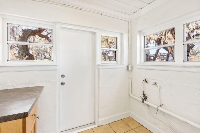 entryway featuring a healthy amount of sunlight, tile patterned floors, and crown molding