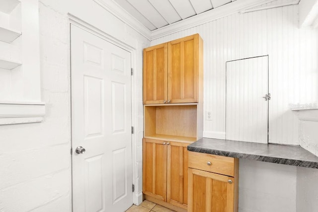 kitchen featuring crown molding, built in desk, and light tile patterned flooring