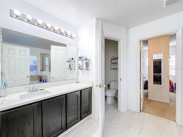 bathroom featuring vanity, a textured ceiling, and toilet