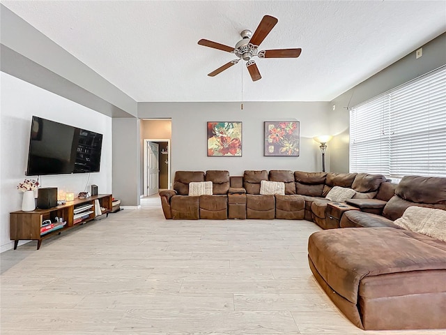 living room with a textured ceiling, light hardwood / wood-style flooring, and ceiling fan