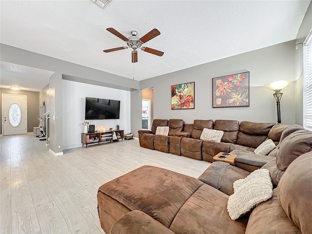 living room with a textured ceiling, light hardwood / wood-style flooring, and ceiling fan