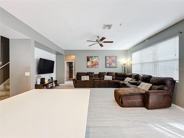 living room featuring ceiling fan and a textured ceiling