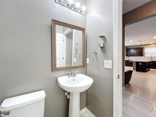 bathroom featuring toilet, sink, hardwood / wood-style floors, and decorative backsplash