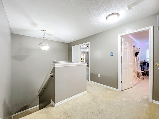 hallway featuring light carpet and a textured ceiling