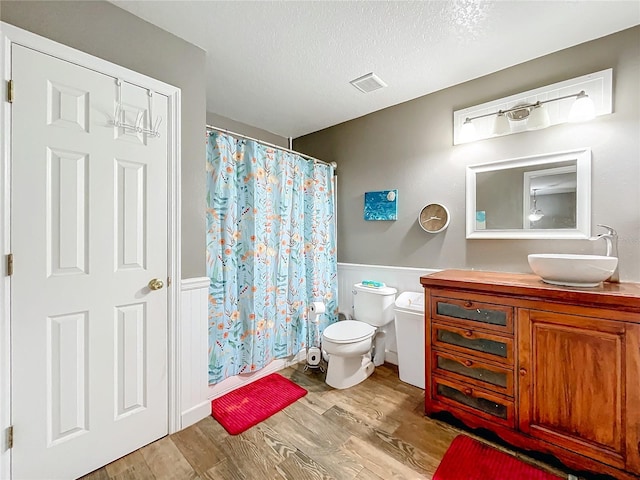 bathroom featuring hardwood / wood-style flooring, vanity, a textured ceiling, curtained shower, and toilet