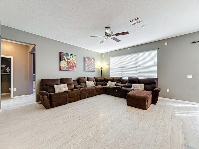 living room with ceiling fan, a textured ceiling, and light hardwood / wood-style flooring