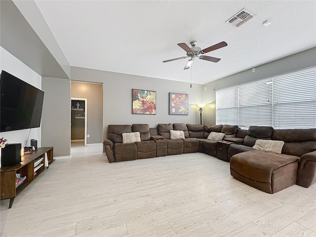 living room featuring a textured ceiling, ceiling fan, and light wood-type flooring