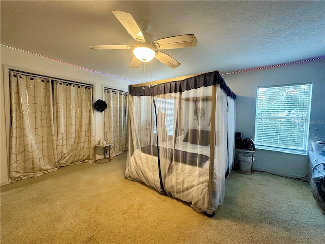 bedroom with ceiling fan, carpet flooring, and a textured ceiling