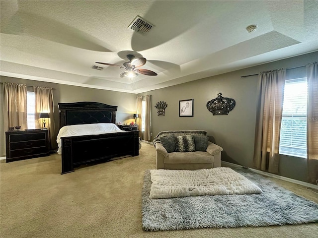 bedroom with multiple windows, carpet floors, a raised ceiling, and ceiling fan