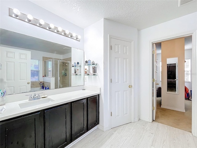 bathroom with an enclosed shower, vanity, hardwood / wood-style floors, and a textured ceiling