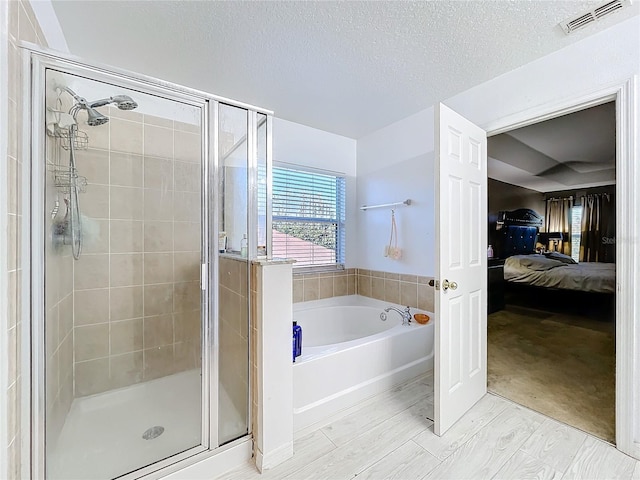 bathroom with wood-type flooring, separate shower and tub, and a textured ceiling