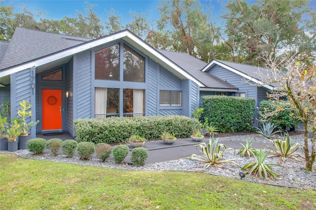 view of front of property with roof with shingles and a front yard