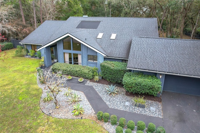 view of front of house with a shingled roof and a front yard