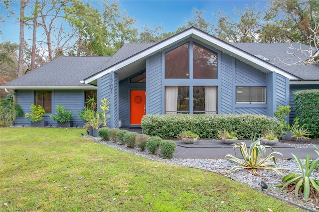 mid-century home featuring a front lawn and roof with shingles