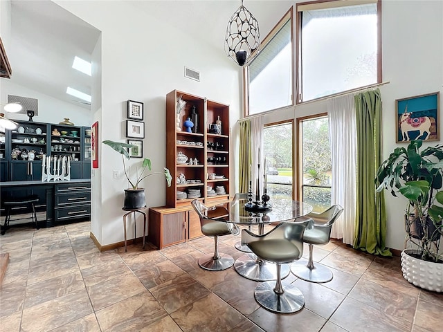 dining room featuring high vaulted ceiling, visible vents, and baseboards