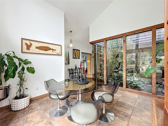 dining area featuring high vaulted ceiling and baseboards