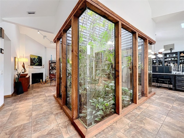 doorway featuring high vaulted ceiling, a fireplace, visible vents, and baseboards