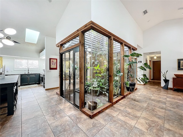 doorway to outside featuring high vaulted ceiling, a skylight, visible vents, and a sink