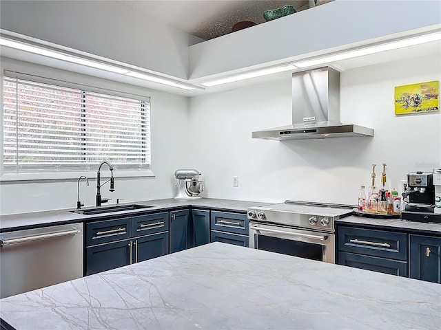 kitchen with blue cabinetry, wall chimney exhaust hood, stainless steel appliances, and a sink