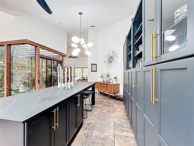 kitchen featuring light stone counters, decorative light fixtures, a breakfast bar area, open shelves, and a kitchen island