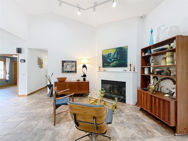 living room featuring high vaulted ceiling, a tile fireplace, and baseboards