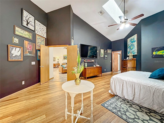 bedroom with high vaulted ceiling, a skylight, visible vents, and light wood finished floors