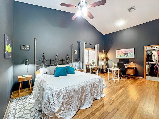 bedroom with high vaulted ceiling, ceiling fan, visible vents, and wood finished floors