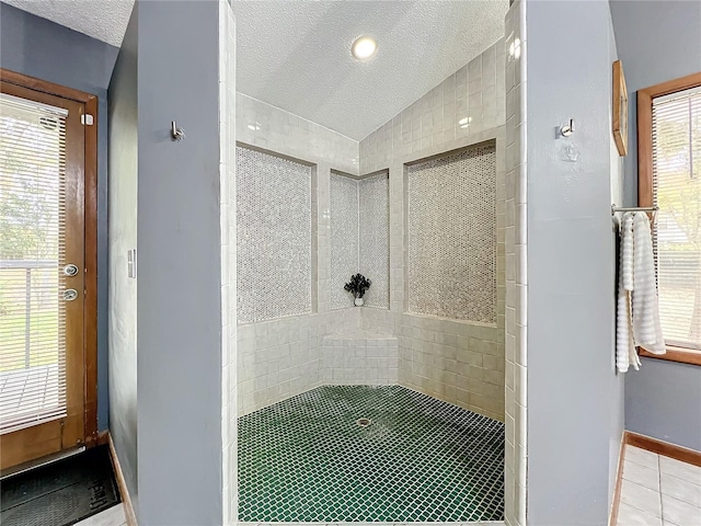 full bath featuring a textured ceiling, baseboards, vaulted ceiling, tile patterned floors, and walk in shower