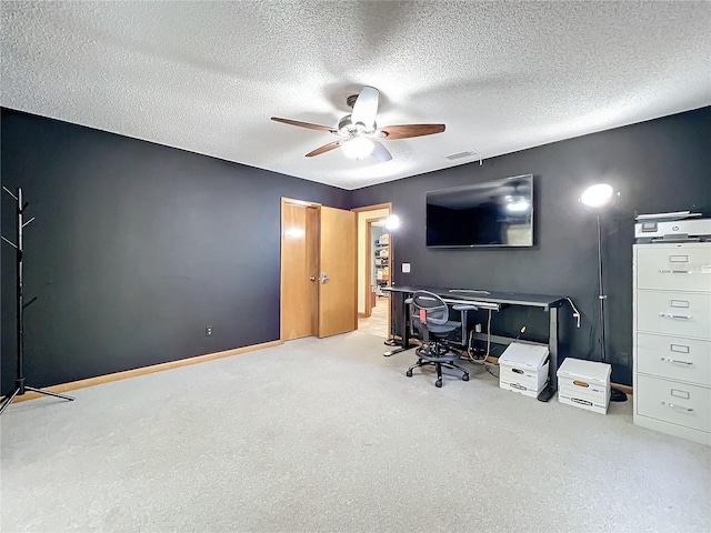 home office with a textured ceiling, baseboards, a ceiling fan, and light colored carpet