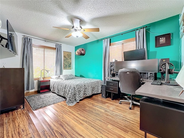 bedroom with ceiling fan, a textured ceiling, and light wood finished floors