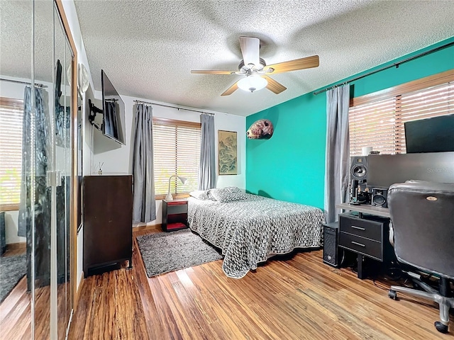 bedroom featuring a ceiling fan, light wood-style flooring, and a textured ceiling