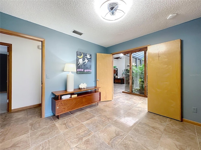 corridor with a textured ceiling, visible vents, and baseboards